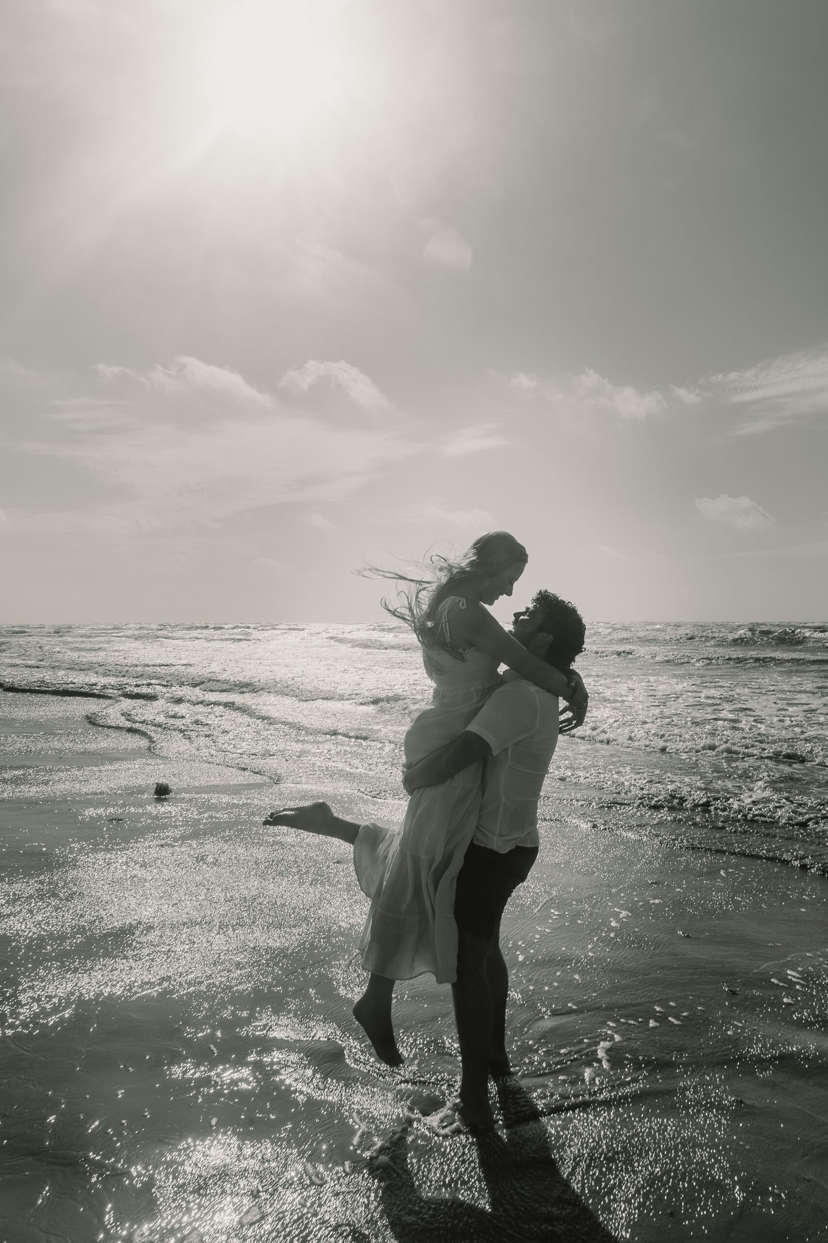 Houston engagement photo locations -couple on the beach, male holding female up and spinning while hair blows in the wind